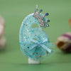 A light blue glittery fabric decoration shaped like the number six with a silver crown and blue jewels, used for a birthday c