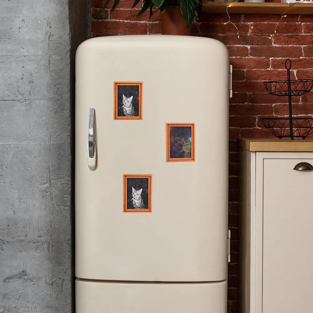 A cream-colored fridge magnet featuring three framed illustrations of cats on a white cabinet.