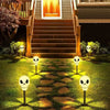 A pathway lined with skull solar lights leading up to a wooden staircase and house entrance.