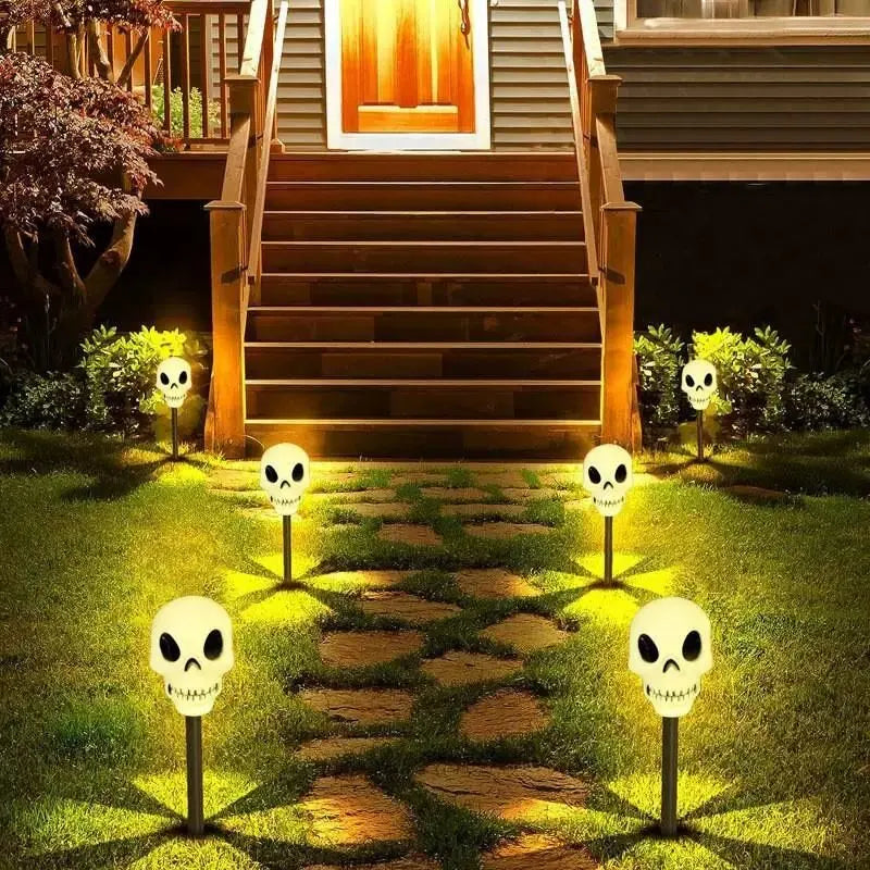 A pathway lined with skull solar lights leading up to a wooden staircase and house entrance.