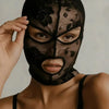 A model wearing a black Venetian Gothic lace mask with floral detailing.