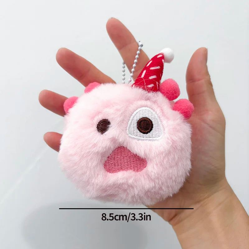 A pink fluffy plush doll with a red conical hat is held in a hand.