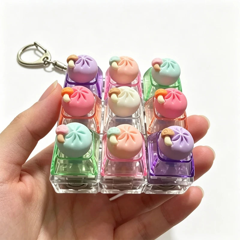 Una mano sostiene un juego de llaveros de teclado de dumplings táctiles y coloridos con varios colores pastel.