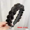 A close-up of a dark brown braided hair band with a black elastic band shown being held by a hand.