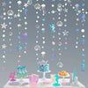Iridescent mermaid and jellyfish party streamers hanging against a gray background with treats.