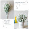 A close-up of fluffy white lavender artificial flowers in a white pot, displayed against a light background.