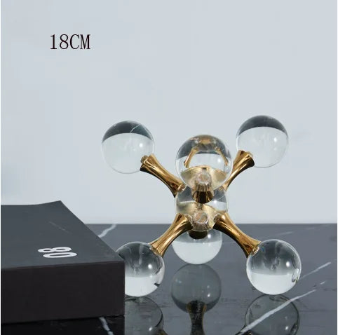 A minimalist molecular sculpture desk decor featuring gold-toned glass spheres on a dark surface.