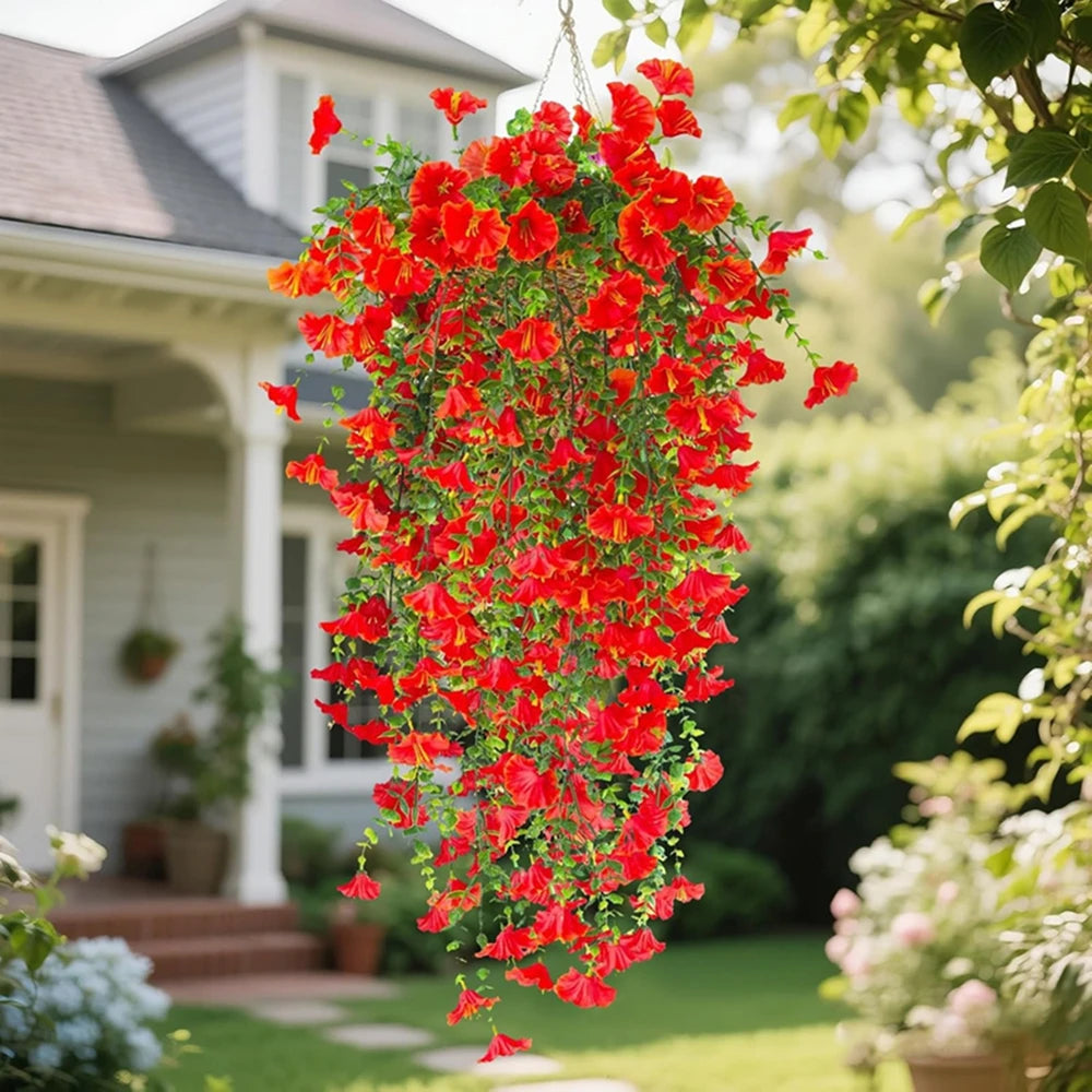 A vibrant cascade of red artificial morning glory vine hanging outdoors near a house.