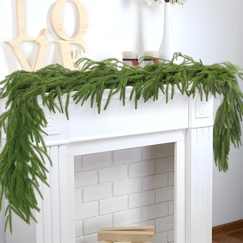 Green Norfolk pine Christmas garland draped across a white fireplace mantel