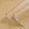 Roll of self-adhesive PVC wallpaper film with a wood grain texture shown on a wooden surface.
