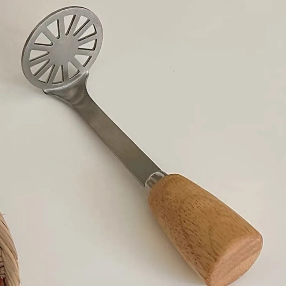 A manual wooden potato and pumpkin masher with a metal sieve end and a wooden handle.