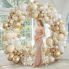 A large balloon garland featuring beige and gold balloons decorated with white flowers and dried foliage.