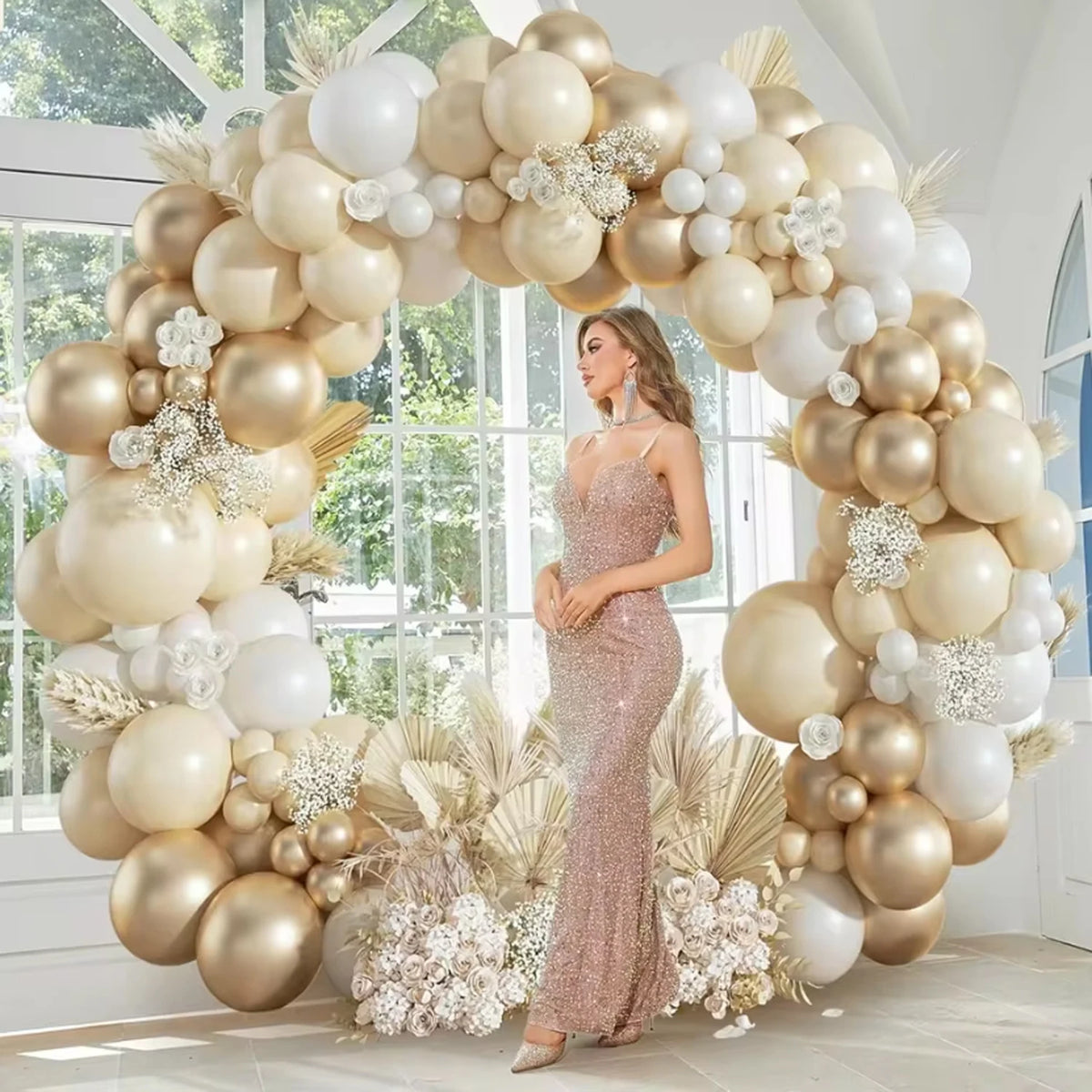 A large balloon garland featuring beige and gold balloons decorated with white flowers and dried foliage.