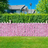 A pink artificial cherry blossom privacy fence screen bordering a green lawn and a residential house.