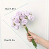 A hand holds a bouquet of light purple silk peonies against a white background.
