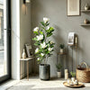 A tall artificial magnolia tree with white silk flowers in a dark pot displayed indoors.