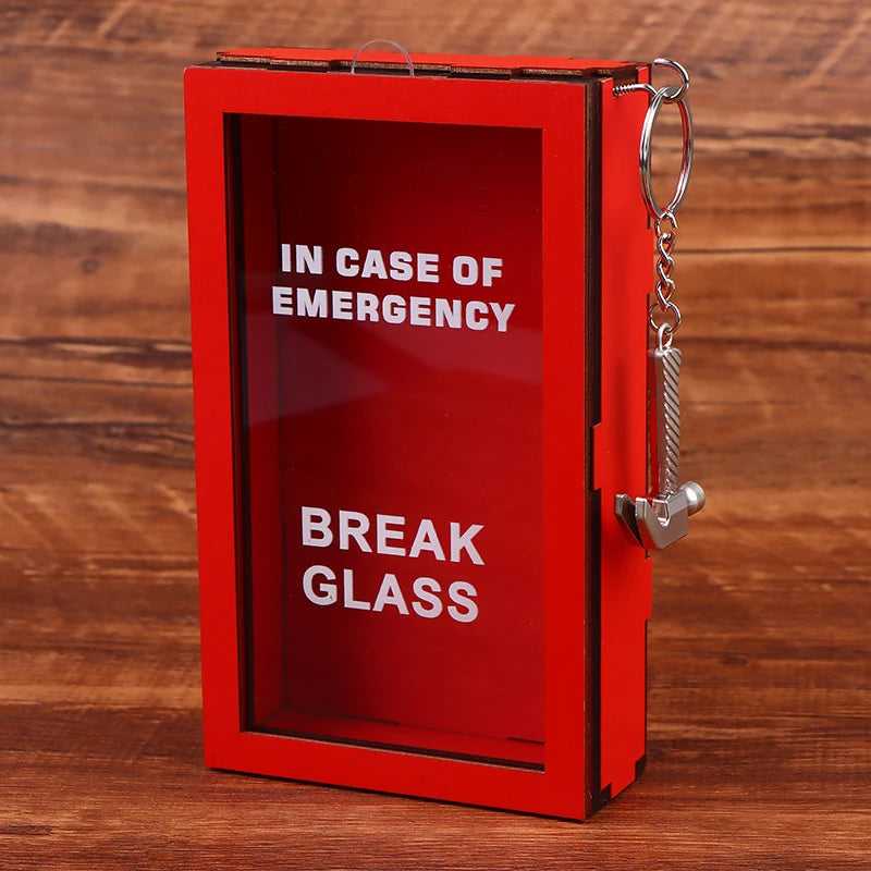 Caja de regalo roja con ventana transparente y cadena plateada, con la inscripción EN CASO DE EMERGENCIA ROMPER ESCARBAJO.