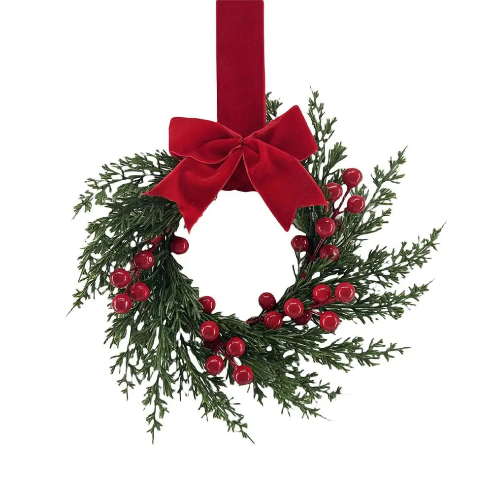 A 10-inch artificial Christmas wreath made of green foliage, red berries, and a large red velvet bow.