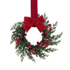 A 10-inch artificial Christmas wreath made of green foliage, red berries, and a large red velvet bow.