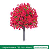A dense bouquet of bright pink artificial petunias arranged on a black ground stake.