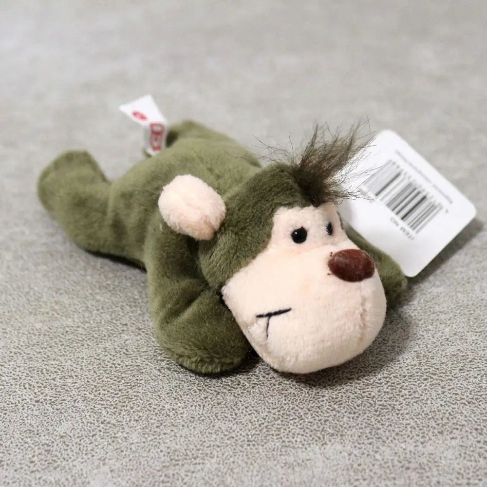 A soft green plush animal toy resembling a bear or similar creature is displayed on a gray surface.