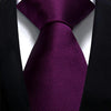 A close-up shot of a deep purple silk necktie tied in a formal knot against a black suit jacket.