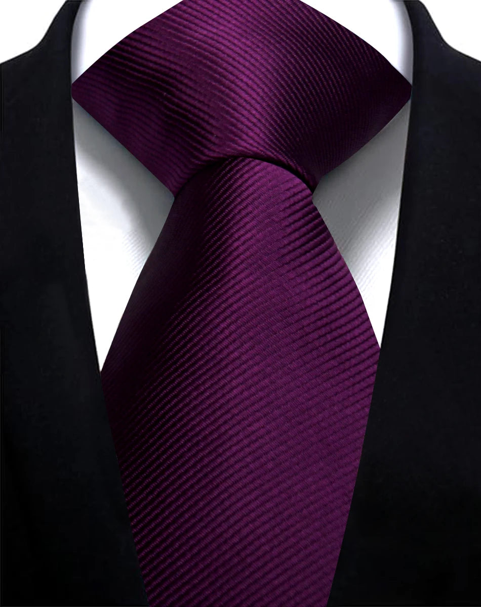 A close-up shot of a deep purple silk necktie tied in a formal knot against a black suit jacket.