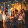A group of young adults celebrating outdoors under string lights with glowing LED light-up balloons.