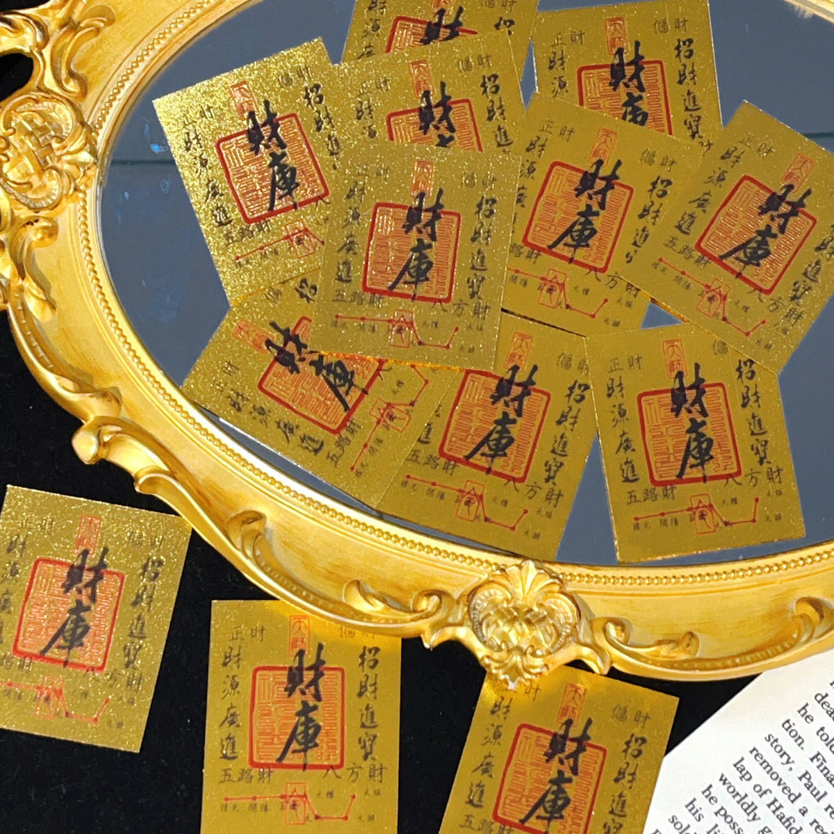 A close-up of gold-colored wealth amulets or stickers displayed in a ornate gold frame.