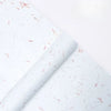 Roll of white decorative packaging paper with scattered pink flower petals.