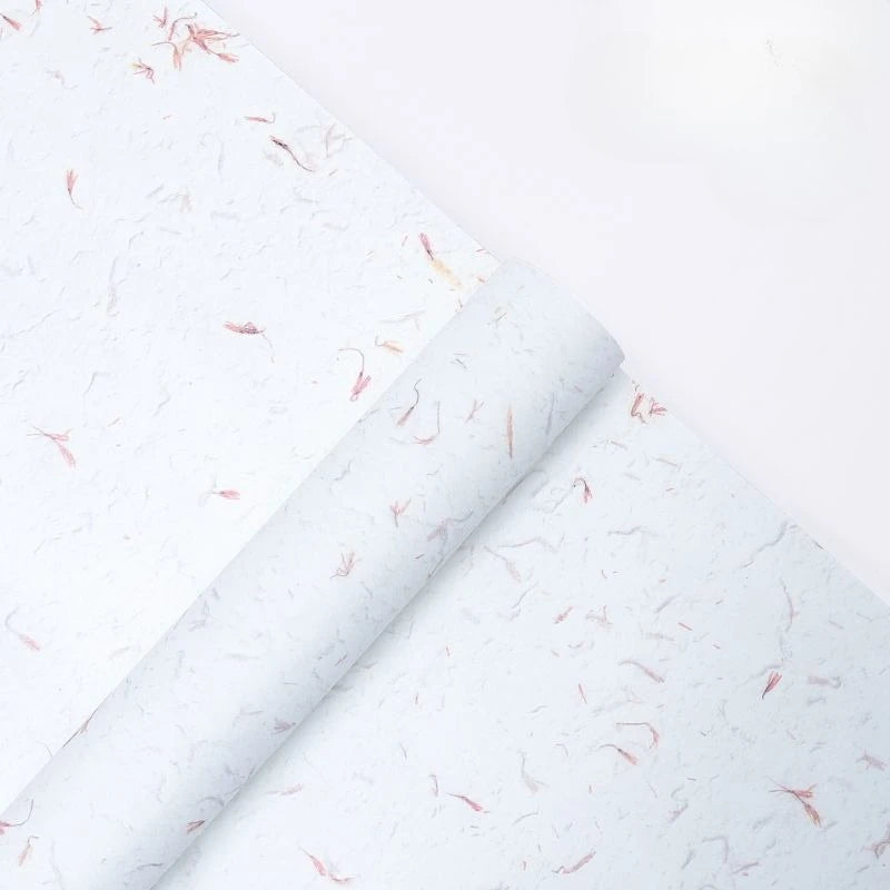 Roll of white decorative packaging paper with scattered pink flower petals.