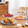 A 3-tier detachable cake stand for desserts and fruit featuring pink and gold accents on a wooden table.