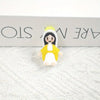 A small resin statue of the Virgin Mary with a yellow halo and robe, displayed on a white textured surface.