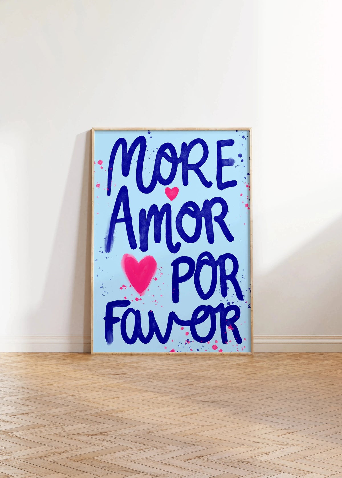 A vertical canvas print featuring the hand-painted text MORE AMOR POR FAVOR in blue and pink on a white background.