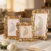A set of three golden resin photo frames featuring elegant floral designs and greenery on a marble surface.