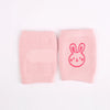 Pair of pink knitted knee pads with a rabbit face design for crawling infants