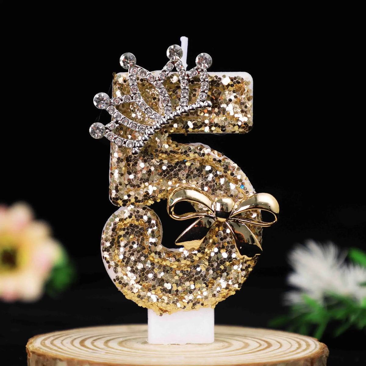 Gold glitter number cake topper candles with a rhinestone bow on a white base