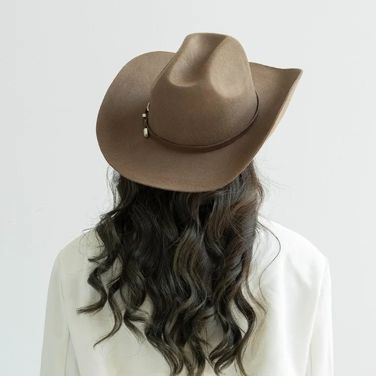 A brown wool cowboy hat with a leather band is shown from the back, worn by a person with long dark hair.
