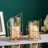 Elegant metal and glass candle holders with lit candles displayed on a dark surface.