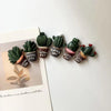 A set of seven small, green cactus-shaped fridge magnets with gold accents.