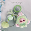 A cute green heart plush keychain charm with pink accents and a green ring.