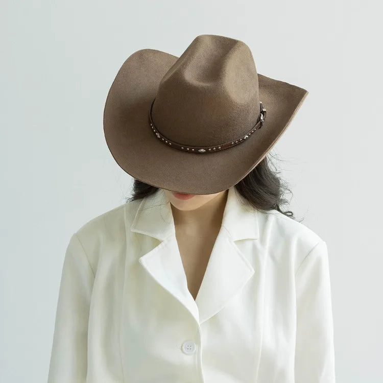 A woman wearing a brown wool cowboy hat with a studded leather band and a white collared shirt.