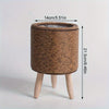 A rustic rattan planter with a round woven top and wooden legs, measuring 14cm in diameter.