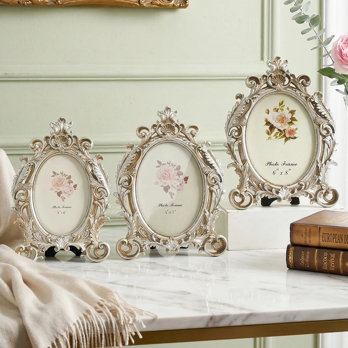 A set of vintage gold oval resin picture frames displayed on a white marble surface.