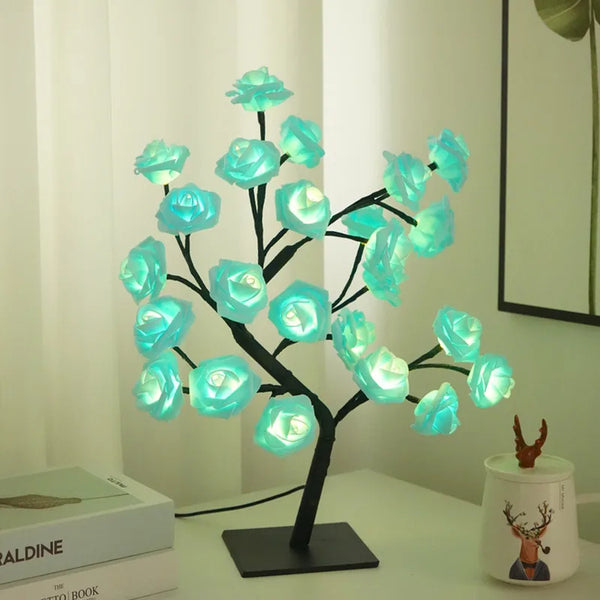 Escultura de árbol oscuro con flores de rosa azules brillantes, usada como luz nocturna decorativa.