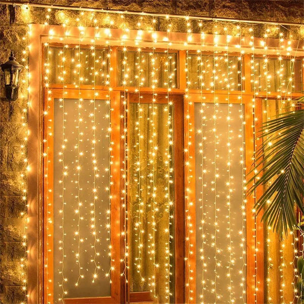 A wooden door decorated with vertical strands of warm fairy lights creating a glowing curtain effect.