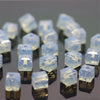 Square cut clear glass crystal beads used for jewelry making displayed on a dark surface