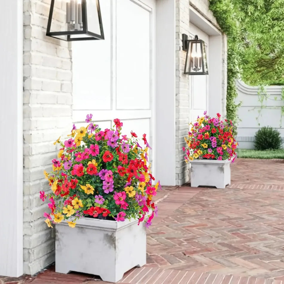 Une vitrine vibrante de marguerites artificielles et de fleurs colorées dans des pots blancs à côté d'un mur de briques blanc