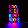 Neon sign spelling out COOL KIDS READ BOOKS with vibrant pink, yellow, and blue lights.