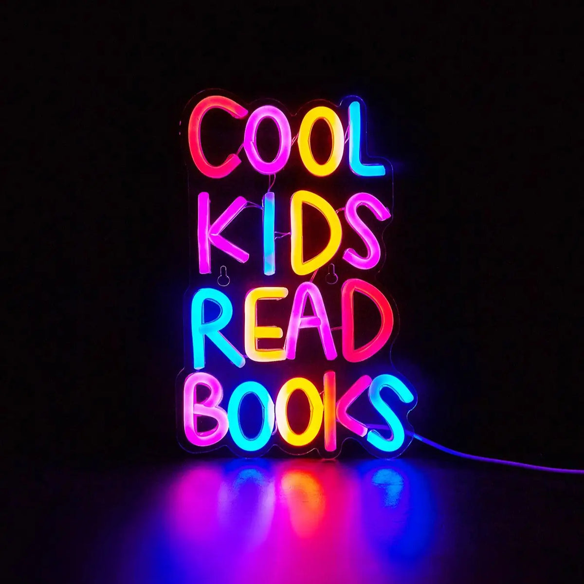 Neon sign spelling out COOL KIDS READ BOOKS with vibrant pink, yellow, and blue lights.